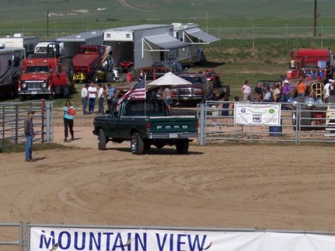 1972 Ford Ranchero - A green Ford pickup truck is parked in a dirt lot with other vehicles and people in the background.