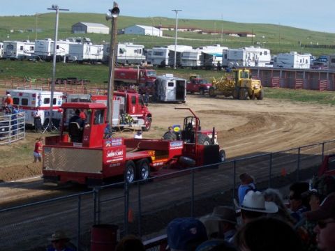 1972 Ford Ranchero - A red tractor is pulling a trailer during an event, with numerous RVs parked on a grassy hill in the background.