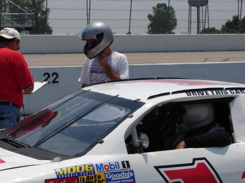 1992 Ford Taurus - A race car driver prepares for the track, with various sponsor decals visible on the vehicle's exterior.