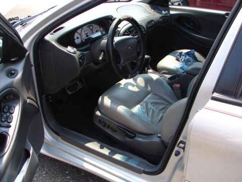 1992 Ford Taurus - The interior of a silver Ford Taurus is shown, with a focus on the dashboard and driver's seat. The odometer reads 1996.