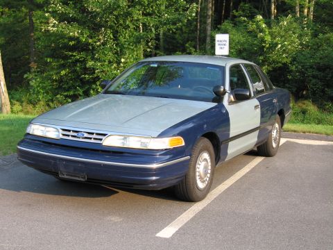 1991 Ford LTD Crown Victoria - A two-tone Ford Crown Victoria is parked in a lot with a "Principal Parking Only" sign overhead.