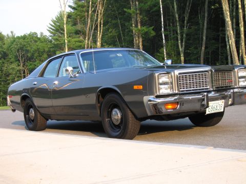 1991 Ford LTD Crown Victoria - This 1977 Dodge Monaco sedan features a distinctive chrome grille and bumper, parked outdoors with a wooded background.