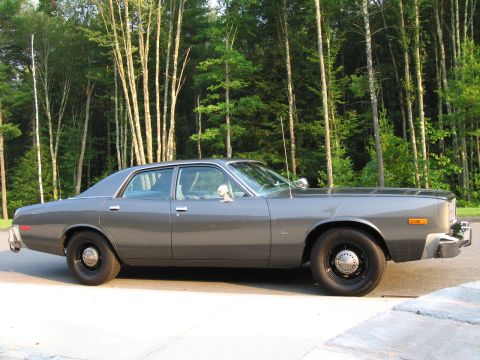 1991 Ford LTD Crown Victoria - Side view of a 1977 Dodge Monaco sedan parked outdoors with trees in the background.