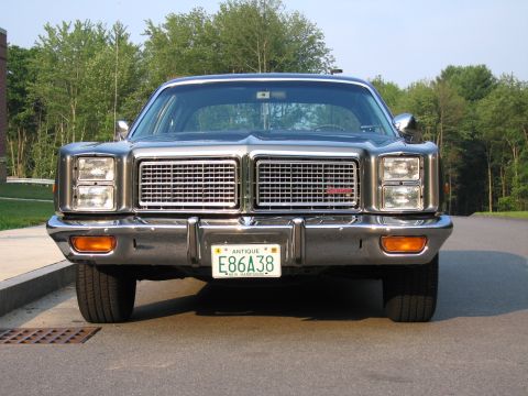 1991 Ford LTD Crown Victoria - A vintage sedan with a prominent chrome grille is parked on a road with trees in the background.