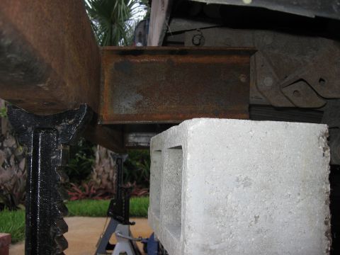 1974 Ford F-100 - Vehicle frame is rusted and supported by jack stands and a concrete block.