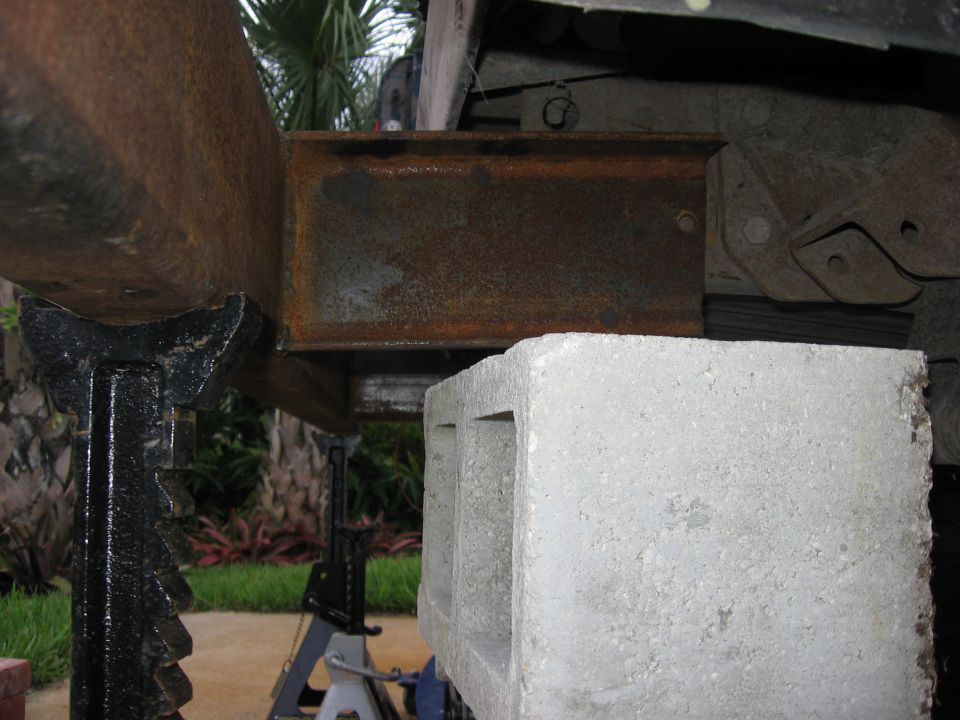 Rusted metal frame supported by jack stands and a concrete block