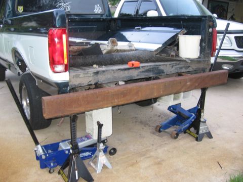 1974 Ford F-100 - A truck's rear bumper is removed and supported by jacks, with another vehicle visible in the background.