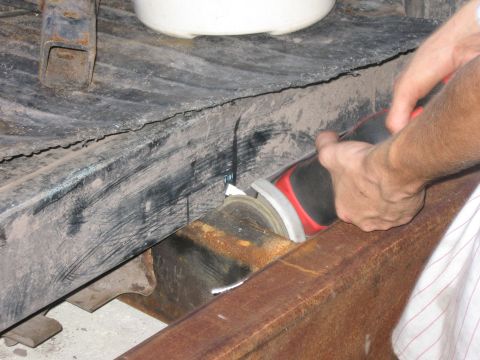 1974 Ford F-100 - Hands using an angle grinder to cut a rusty metal frame.