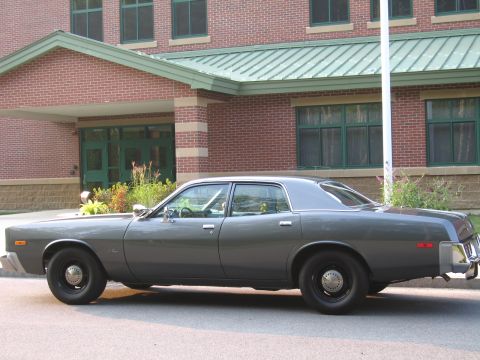 1991 Ford LTD Crown Victoria - This gray sedan is parked on the street in front of a brick building with green trim.