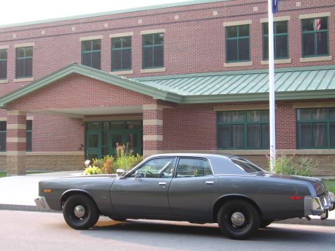 1991 Ford LTD Crown Victoria - This 1977 sedan is parked outside a brick building with a green roof and trim.