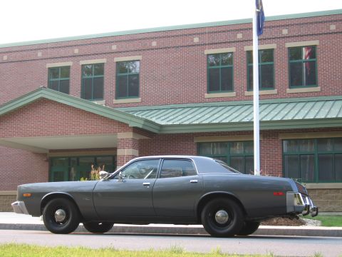 1991 Ford LTD Crown Victoria - A side profile of a 1977 Dodge Monaco sedan is shown parked in front of a brick building with green trim.