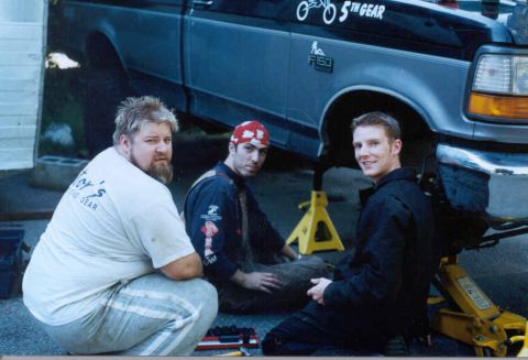 1995 Ford F-150 - Three men are gathered around a 1995 Ford F-150 truck that is elevated on jack stands.
