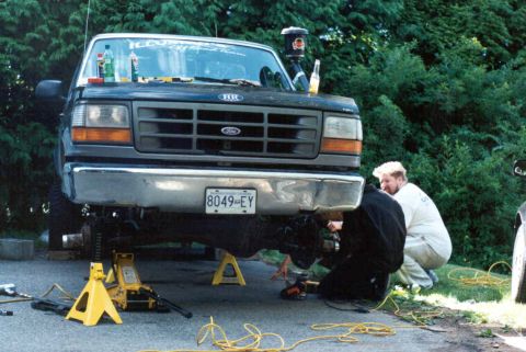 1995 Ford F-150 - A 1995 Ford F-150 is shown with its front end elevated on jack stands as mechanics work on the suspension.