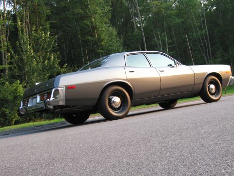 1991 Ford LTD Crown Victoria - A vintage gray sedan is viewed from the rear three-quarter angle with a wooded area behind it.