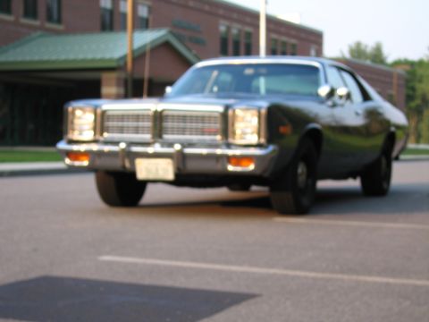 1991 Ford LTD Crown Victoria - This dark sedan, likely a 1977 model, is seen from the front with its prominent chrome grille and rectangular headlights.