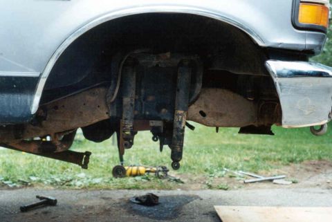 1995 Ford F-150 - The front suspension of a truck is shown with the shocks detached, revealing the frame and surrounding components.