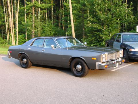 1991 Ford LTD Crown Victoria - A 1977 Dodge sedan is parked in a lot with trees in the background.