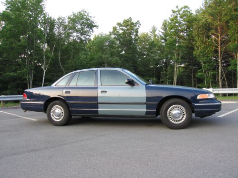1991 Ford LTD Crown Victoria - Two-tone Ford Crown Victoria parked outdoors with trees in the background.