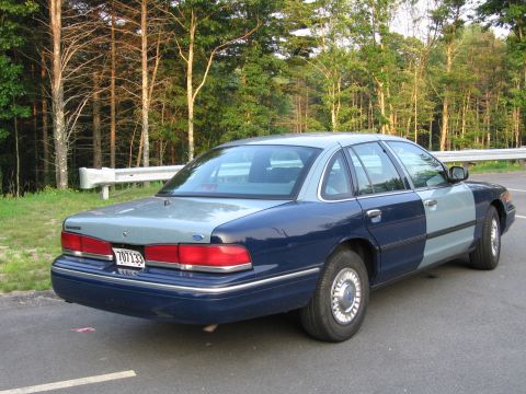1991 Ford LTD Crown Victoria - Rear view of a two-tone Ford Crown Victoria parked next to a guardrail and trees.