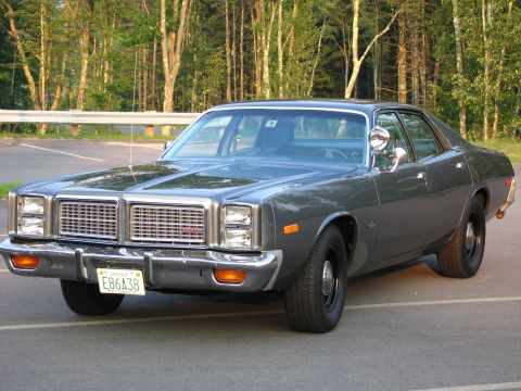 1991 Ford LTD Crown Victoria - Front three-quarter view of a dark grey late-1970s Dodge Monaco-style full-size four-door sedan on black steel wheels, with stacked quad he…