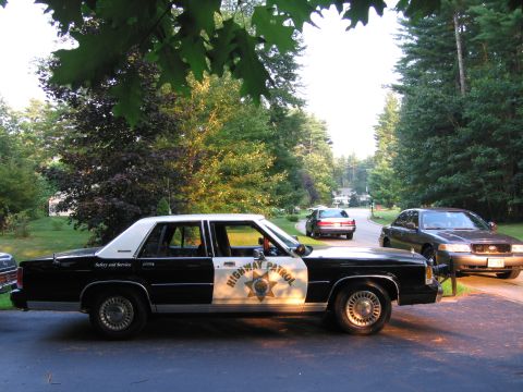 1991 Ford LTD Crown Victoria - A 1991 Ford Crown Victoria LTD highway patrol car is parked on a driveway, with two other vehicles visible in the background.