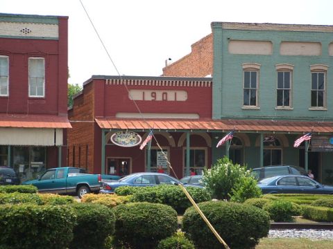 1966 Ford Ranchero - A street scene shows historic brick buildings and parked vehicles under a bright sky.