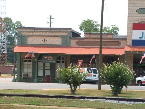 1966 Ford Ranchero - A white van is parked in front of a store with American flags displayed.