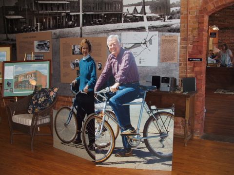 1966 Ford Ranchero - A museum exhibit features cardboard cutouts of a man and woman posed on bicycles, set against a backdrop of historical town scenes.