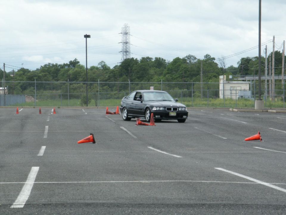 Black BMW E36 coupe navigating a cone course in a parking lot