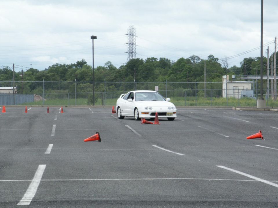 White Acura Integra coupe navigating a cone course in a parking lot