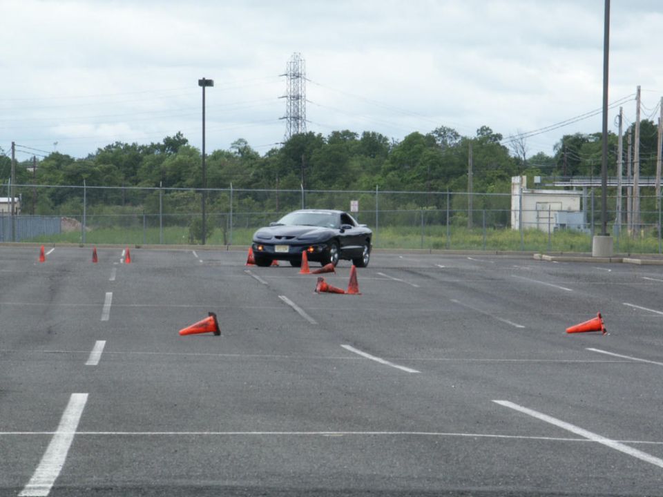 Black Pontiac Firebird Trans Am in a parking lot with orange cones