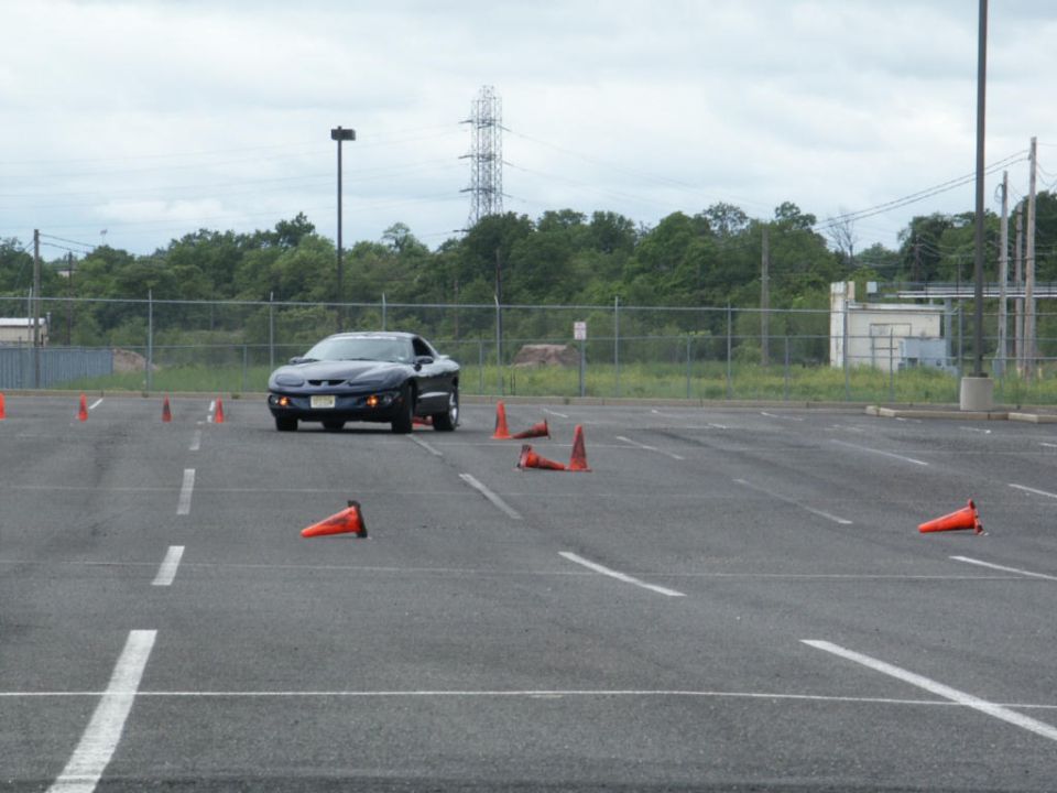 Dark blue Pontiac Firebird driving through a cone course in a parking lot