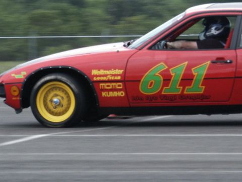 2001 Mercury Grand Marquis - A red race car with yellow wheels and green number 611 speeds down the track.