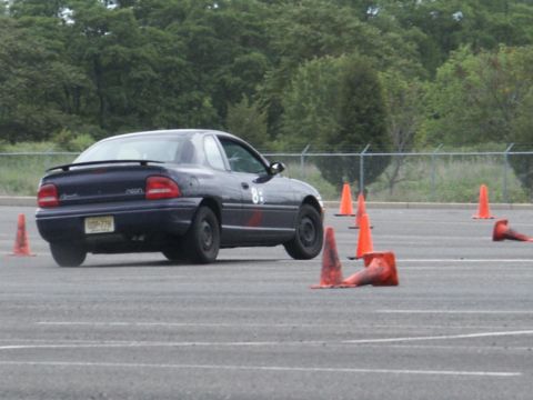 2001 Mercury Grand Marquis - A dark blue Dodge Neon is seen from the rear, participating in a timed driving event with orange cones marking the course.