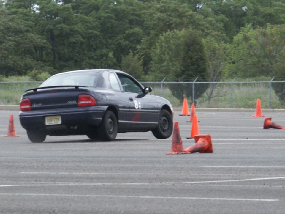 Dark blue Dodge Neon with number 85 on the door, navigating an autocross course with orange cones