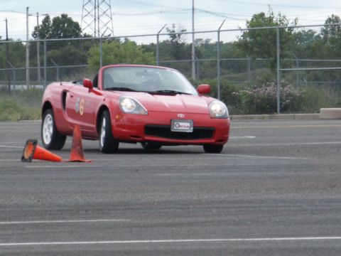 2001 Mercury Grand Marquis - A red convertible sports car navigates a course marked by orange traffic cones on a paved surface.