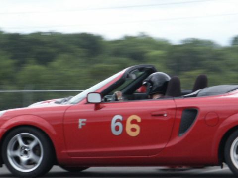 2001 Mercury Grand Marquis - Red convertible sports car with racing number 66 on the door and a driver wearing a helmet.