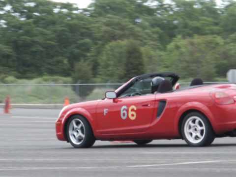 2001 Mercury Grand Marquis - A red convertible with racing numbers is seen on a paved track with orange cones in the background.