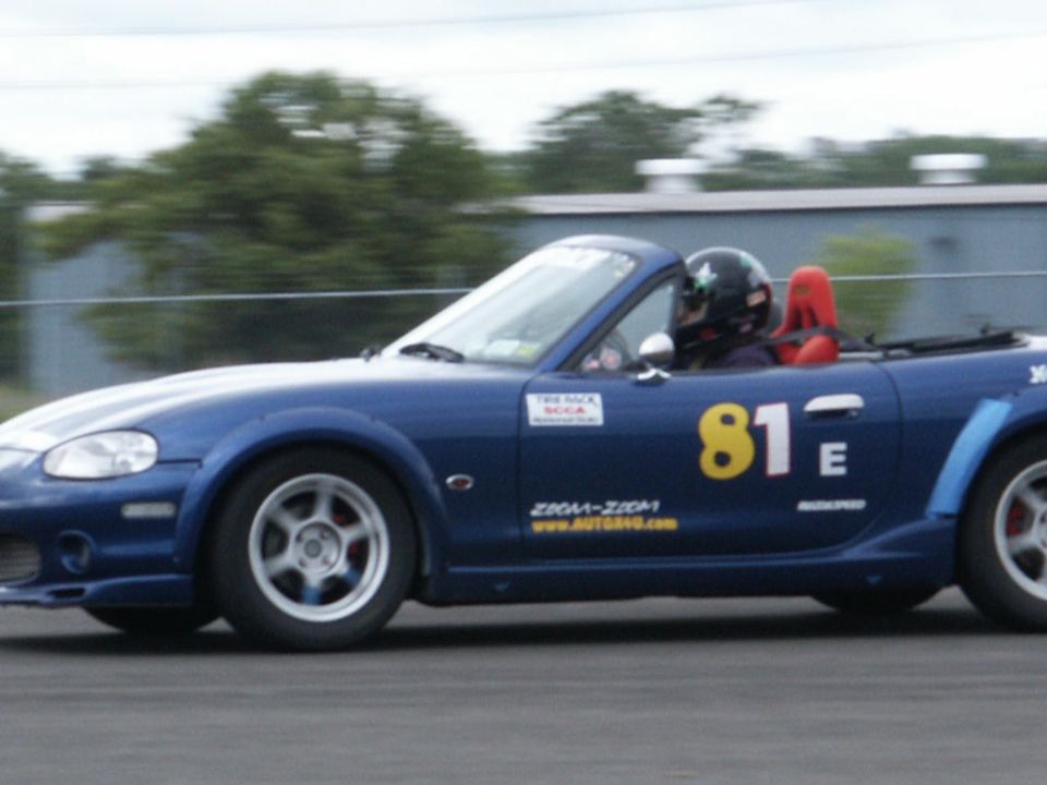 Blue convertible race car with number 81 on the door, driver wearing a helmet