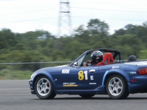 2001 Mercury Grand Marquis - A blue convertible with racing decals is captured in motion on a track.