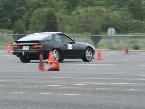 2001 Mercury Grand Marquis - A black coupe, possibly a Porsche 944, is seen on a race track with orange cones marking the course.