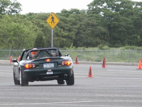 2001 Mercury Grand Marquis - A green convertible sports car navigates a course marked by traffic cones, with a pedestrian crossing sign visible in the background.