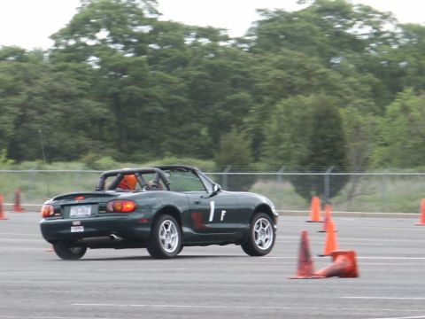 2001 Mercury Grand Marquis - Dark green convertible sports car with roll bar and racing number on the door navigates a course marked by orange cones.