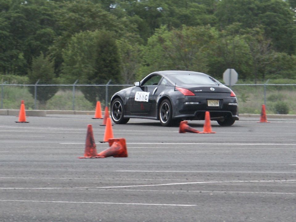 Black Nissan 350Z with number 288C on the door, navigating an autocross course with orange cones