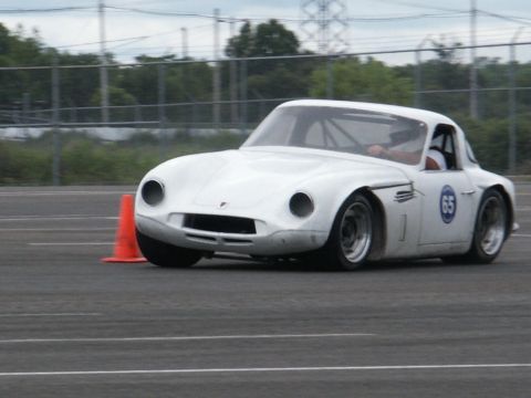 2001 Mercury Grand Marquis - A white sports car, identified by the number 65 on its door, is seen in motion on a paved track, likely during a timed event or race.