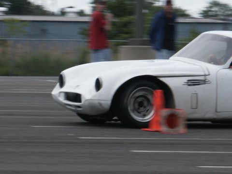 2001 Mercury Grand Marquis - White sports car maneuvering around an orange cone during an event.
