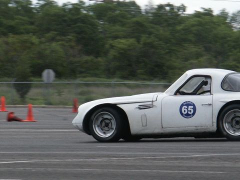 2001 Mercury Grand Marquis - A white vintage race car with the number 65 on its side navigates a course marked by orange cones.