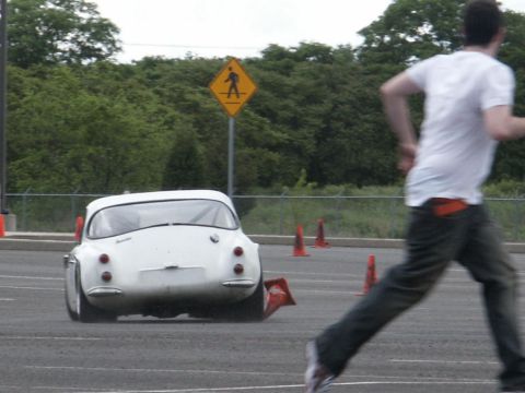 2001 Mercury Grand Marquis - A white vintage car navigates an obstacle course, with a runner blurred in the foreground.