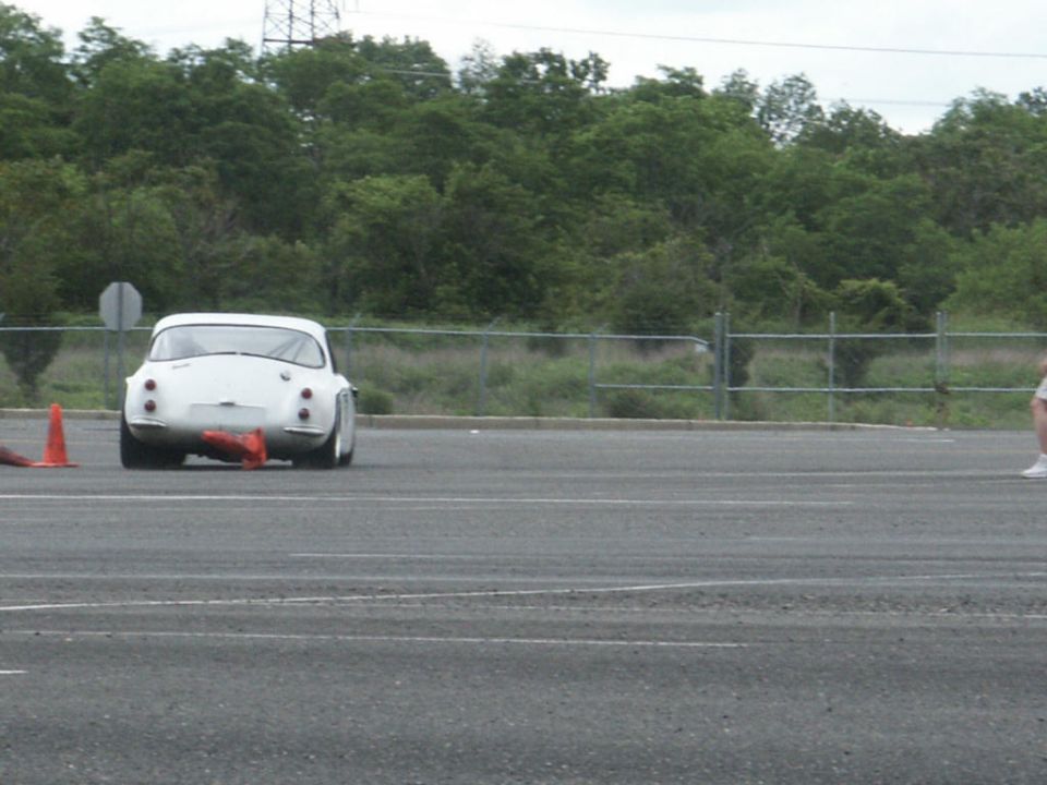 White vintage sports car rear view, orange cones on asphalt