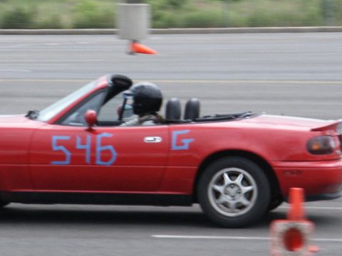 2001 Mercury Grand Marquis - A red convertible sports car with racing numbers is seen on a track with orange cones.